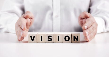 Businessman hands covers the wooden cubes with the word vision