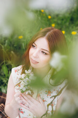 Red-haired girl walks in a spring blooming apple orchard