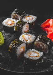 sushi roll with shrimp and rice in plate on black wooden table background