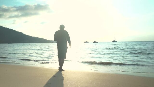 A man walking on the beach Summer evening The sun is going down