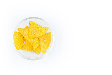 Corn chips into a big glass bowl, nachos isolated on orange  background with copy space ,Top view 