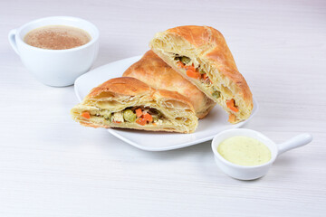 Puff pastry with vegetables and cheese displayed on white wooden background