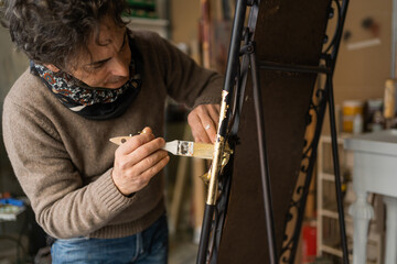 Man applying a gold foil using a brush during a restoration of a mirror - arts and decoration concept