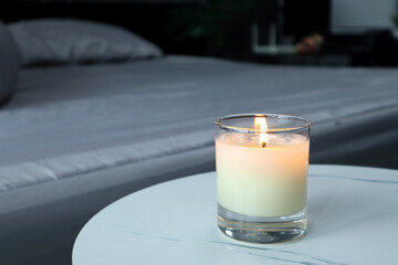 Obraz na płótnie Canvas luxury lighting aromatic scented candle is on the mable table to creat romantic and relax ambient in the grey bedroom with background of grey bed and pillow on valentine day