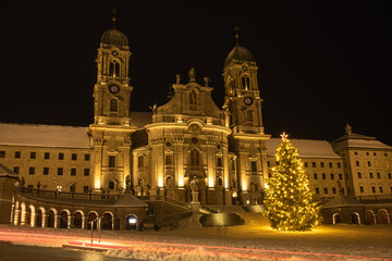 Fototapeta na wymiar Illuminated swiss abbey of Einsiedeln in snowy Christmas time and winter night
