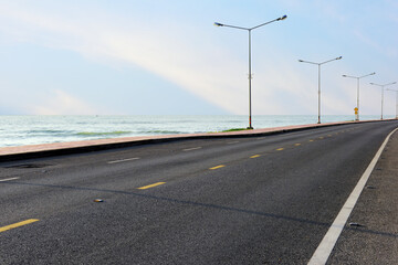 Empty asphalt road with marking line for given direction and sea landscape. Transportation concept and summer travel holiday idea