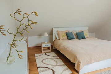 Simple white bedroom on the top floor. Small magnolia branch with buds. Bedroom decoration in...