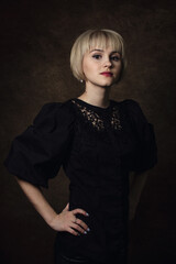Portrait of a girl in a black dress. A girl with a short haircut. Woman portrait on brown background