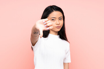 Teenager Chinese woman isolated on pink background showing thumb down with negative expression