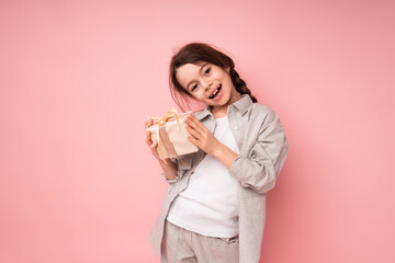 Cheerful beautiful girl smiling and laughing holding a small gift with a bow and tilting her head to one side