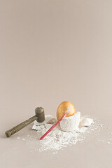 Creative composition with Easter golden egg, hammer, nail and old barrel with treasure. Minimal holiday concept