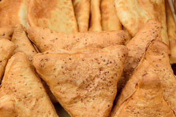 Ready-made samsa with meat filling. Sesame seeds on a baked dough crust. Central Asian cuisines concept.