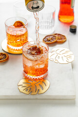 Pouring soda water from a can to make Italian Aperol Spritz cocktail