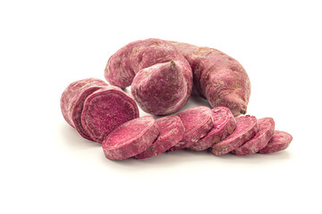 Pile of purple yams or purple sweet potatoes whole and sliced place on white background. Side view. Vegan fruit and healthy fruits concept