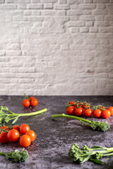 Food photography of fresh cherry tomatoes and bimi on a stone table with brick wall. Still life image with a copy space.