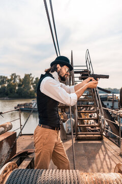 Steampunk. A hero on a river barge surrounded by steel mechanisms. A man with a weapon.