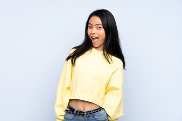 Fototapeta premium Teenager Chinese woman isolated on blue background with surprise facial expression