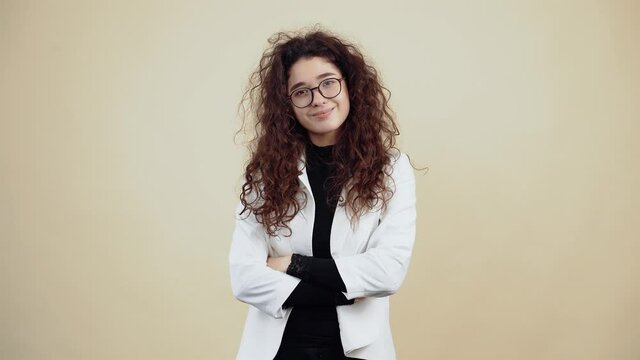 The sleepy young woman with curly hair, with her hands in the middle, is about to fall asleep, blinking often. Young hipster in gray jacket and white shirt,