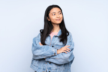 Teenager Chinese woman isolated on blue background looking to the side