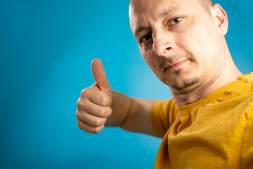 Happy man making selfie and showing thumb up. optimistic man isolated on blue background showing thump up with positive emotions of content and happiness.