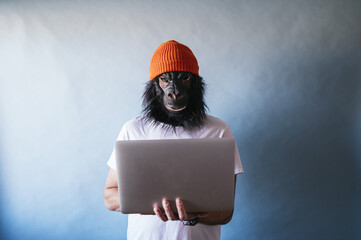 Male in a chimpanzee mask using a laptop