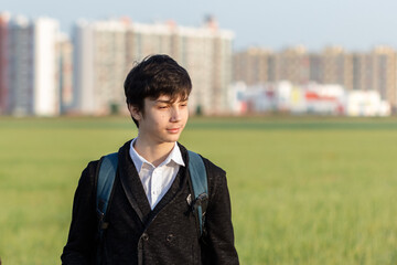 School teenager waiting for a school bus, on his way to school. On the way home from school against the background of the urban landscape