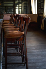 Wooden chairs beside bar counter in a row. Empty cafe in the morning