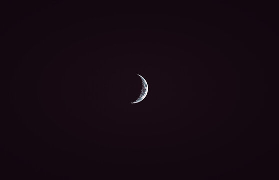 Halbmond fotografiert mit einem starken Teleobjektiv im Winter bei klarer Nacht als Minimalismus Stil. Mond Foto bei Nacht. 