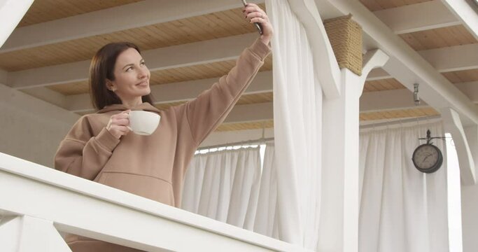 Beautiful Woman Having a Cup of Coffee and Making Selfie Standing on a Terrasse Shot on Red Camera
