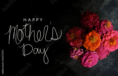 Mother's day card with top view of zinnia flower bouquet on black background with text.