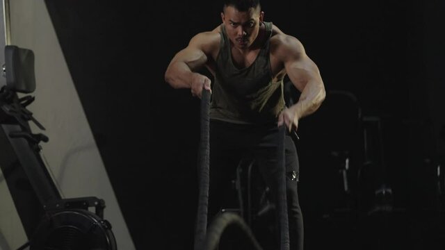 Concept of healthy and sport.Active dedicated motivated male athlete training in gym with battle ropes,determined confident man enjoying bodybuilding achieving goals with healthy lifestyle.4k footage