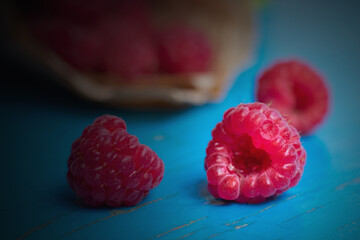 Concept of loving berries, illuminated red tasty raspberries with dark corners