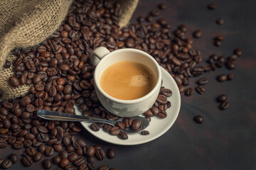 White cup of coffee and coffee bean on dark background. Copy space.