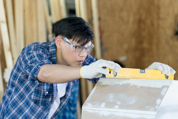 Carpenters are working in a wood factory. Carpenter is using a meter to measure wood sizes. Selective focus on Water level ruler.