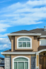 A perfect neighborhood. Houses in suburb at Summer in the north America. Fragment of a luxury house with nice window over blue sky.