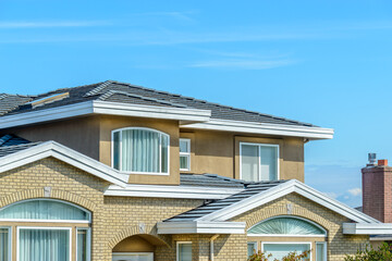 A perfect neighborhood. Houses in suburb at Summer in the north America. Fragment of a luxury house with nice window over blue sky.