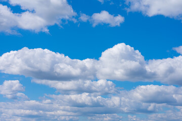 Many white fluffy clouds also known as cumulus on bright summer blue sky. Cloudscape, overcast.