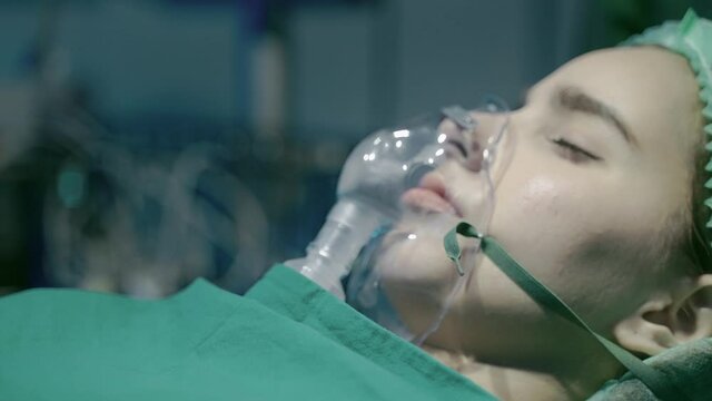 Close-up, a patient in an operating room who is using an oxygen mask to help them breathe.
