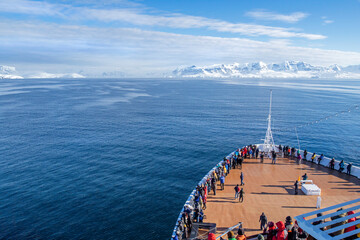 Tourists on Cruise Ship's Bow Deck.  Heading to Antarctic Peninsula, Ice covered Land in the Distance