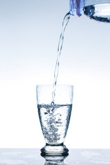 Pour the water from the bottle into the glass