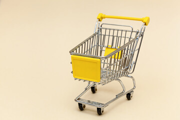 Metal shopping cart on a beige background.