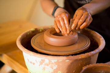 Fototapeta premium Man potter work with clay ware. Young handsome man potter on his workshop. 