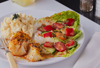 Baked cod fillet with salad and potatoes.
