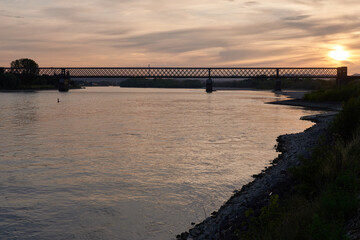 Fototapeta premium Silhouette einer Eisenbahnbrücke über den Rhein im Abendlicht