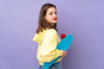 Teenager girl isolated on purple background with a skate