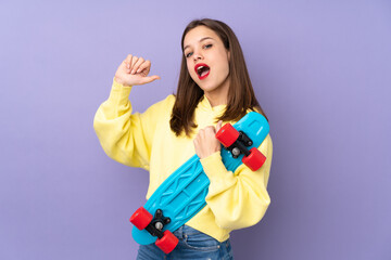 Teenager girl isolated on purple background with a skate with happy expression