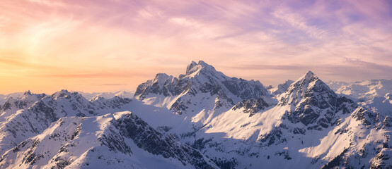 Fototapeta premium Aerial View from Airplane of Blue Snow Covered Canadian Mountain Landscape in Winter. Colorful Pink Sky Art Render. Tantalus Range near Squamish, North of Vancouver, British Columbia, Canada.