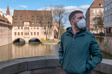 Man in a FFP2 mask in front of the Holy Spirit Hospital (Heilig-Geist-Spital) in Nuremberg (Nürnberg), Bavaria, Germany