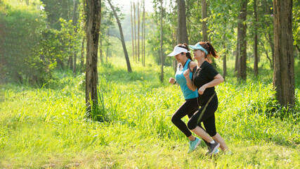 Two Healthy athletic woman running in the Nature park to be more healthy. Healthy and Lifestyle concept. On Green Nature background. .