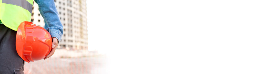 Worker holding red protective helmet at construction site. Long banner